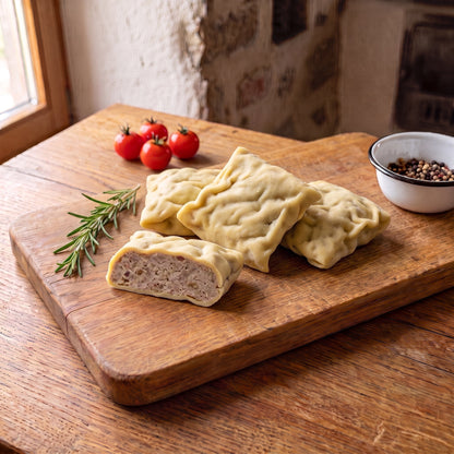 Maultaschen vom Gäu-Weideschwein, vier rohe Maultaschen, eine davon aufgeschnitten, auf einem Eichenbrett