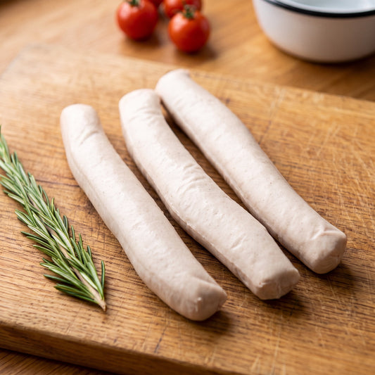 Oberländer Curry-Wurst vom Gäu-Weideschwein, Nahaufnahme der drei hellen Würste auf einem Eichenbrett